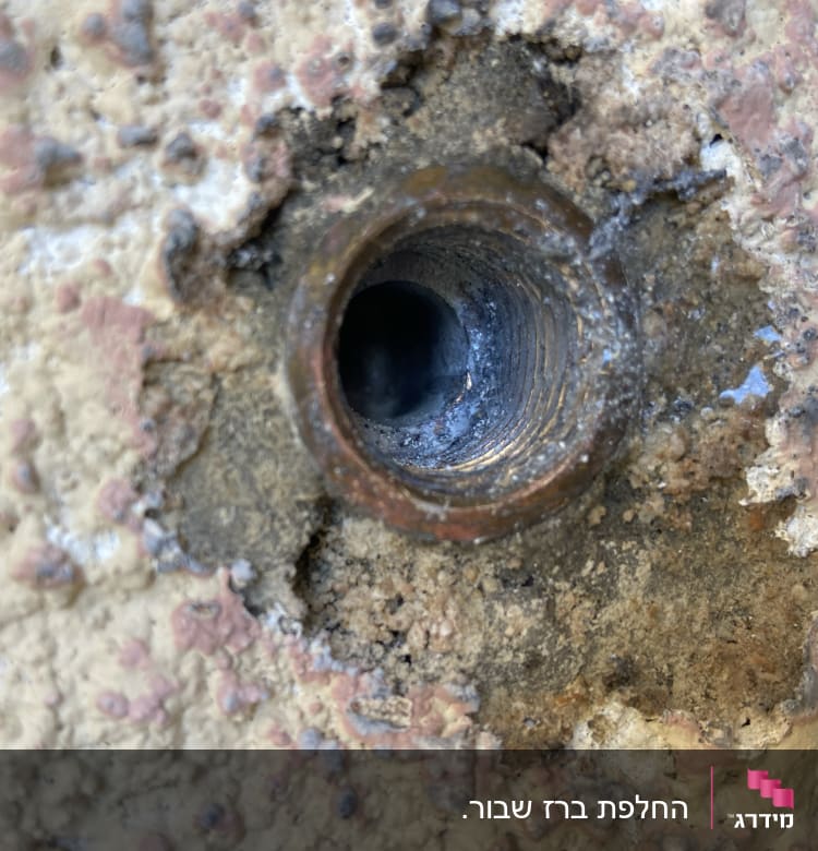 צינור מתכת חלוד בקיר עם חור